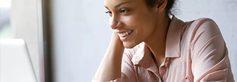 Person smiling while using a laptop.