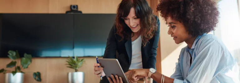 Deux personnes collaborent sur une tablette dans un bureau moderne.