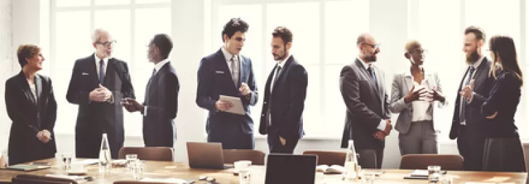 Group of people in business attire discussing around a table.