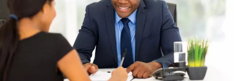 Two people talking at an office desk.