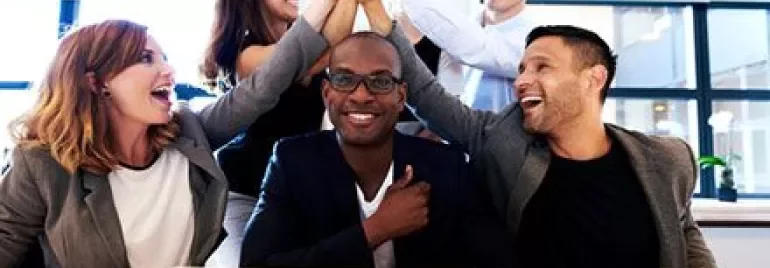 Group of people in an office celebrating with high fives.