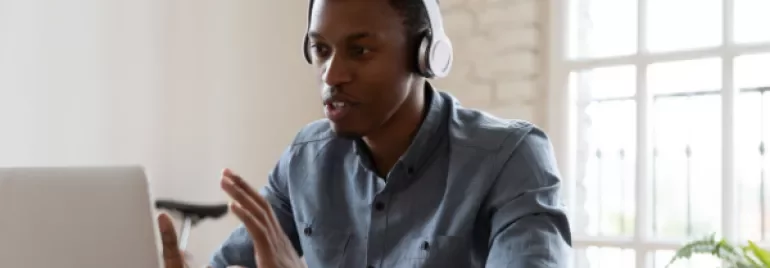 Person with headphones having a video call on a laptop.