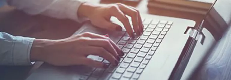 Personne tapant sur un ordinateur portable à un bureau.