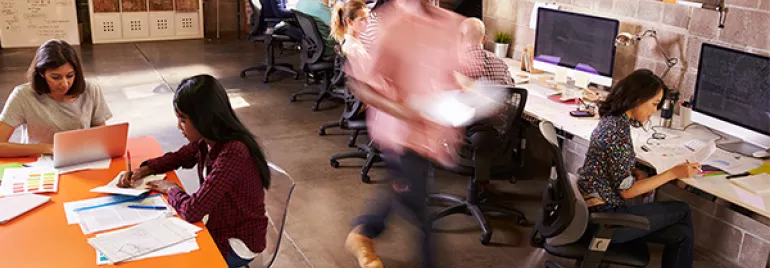 Bureau en espace ouvert avec des personnes travaillant à des bureaux et ordinateurs.