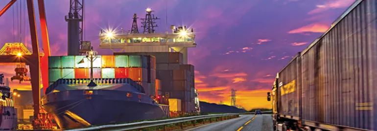 Cargo ship and truck at a port during sunset