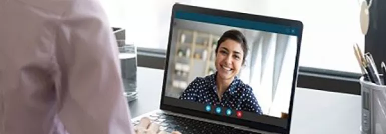 Personne en appel vidéo avec une autre personne sur un ordinateur portable.