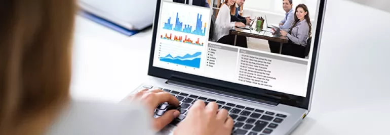 Video conference on laptop with charts and meeting participants.