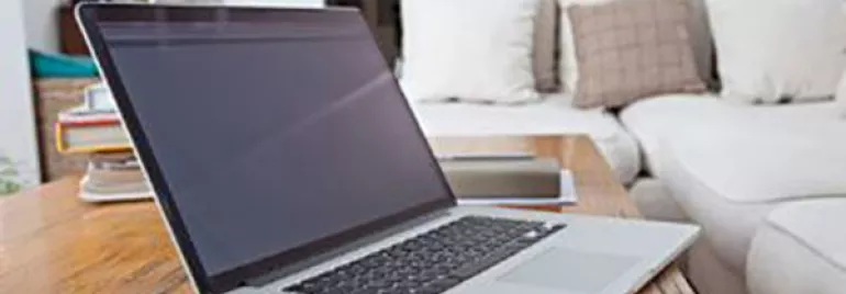 Ordinateur portable et smartphone sur une table basse en bois dans un salon.