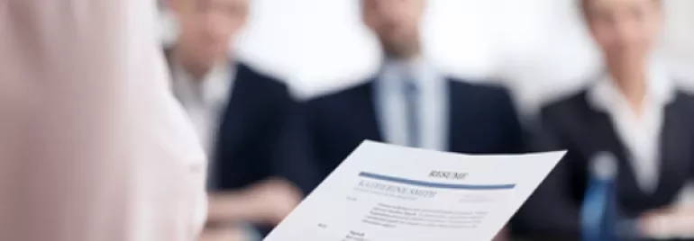 Une personne tient un CV face à un jury d'entretien.