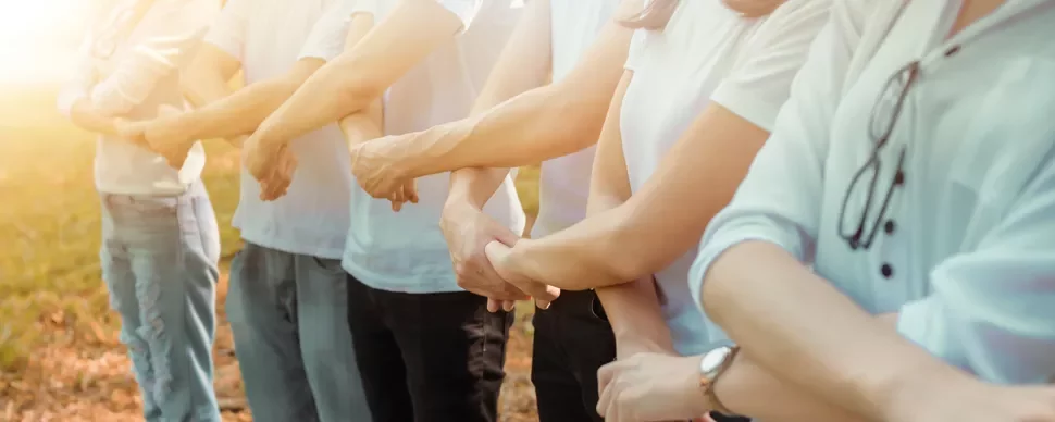 A line of people standing outside, holding each other's arms.