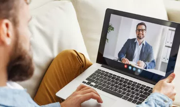 Person on a video call using a laptop, sitting on a couch.