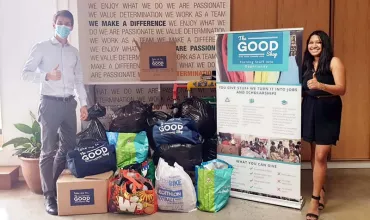 Two people standing beside donation boxes and bags at a charity event.