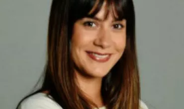 Person smiling, wearing a white shirt with long, brown hair.