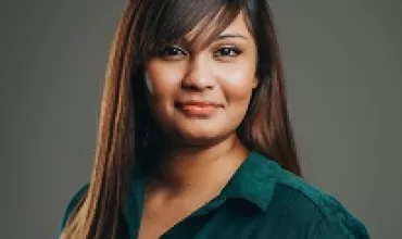 A person with long hair smiling, wearing a green shirt.