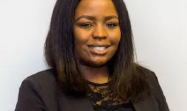 Person smiling in a black blazer, white background