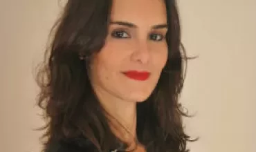 Personne aux cheveux foncés et rouge à lèvres rouge, portant un haut noir.