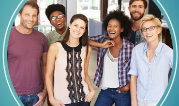 Group of smiling people standing together in a bright room.