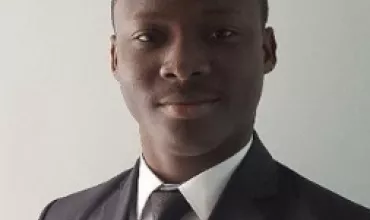 Person in a suit and tie smiling slightly at the camera.