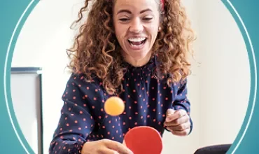 Personne souriant en jouant au tennis de table à l'intérieur.