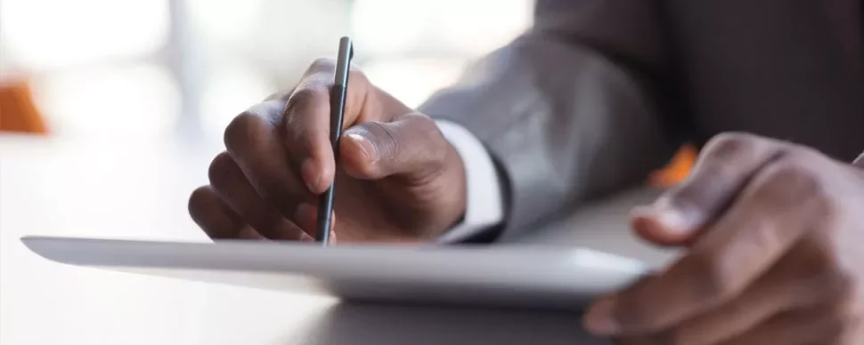 Person writing on a digital tablet with a stylus.
