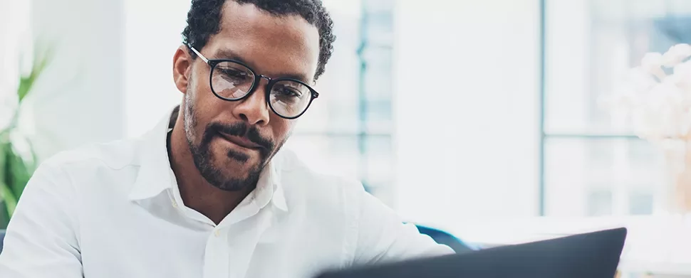 Person with glasses working on a laptop.