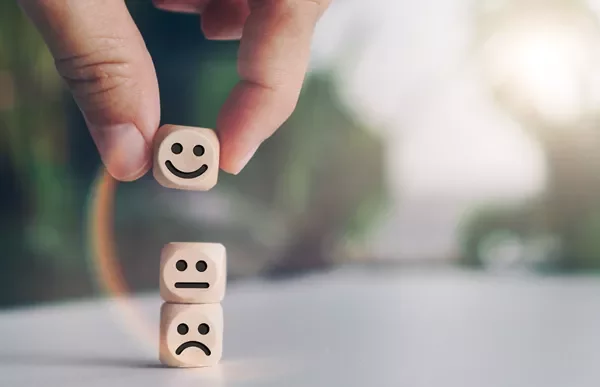 Stacked wooden blocks with happy, neutral, and sad faces.
