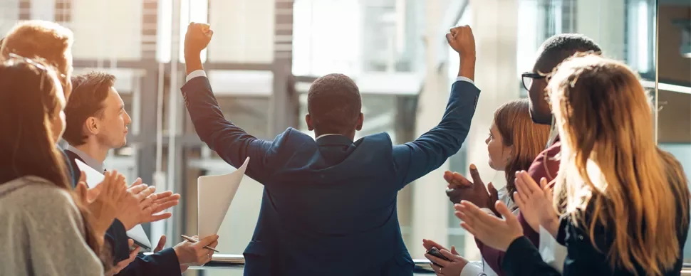 Person celebrating in front of a clapping group.