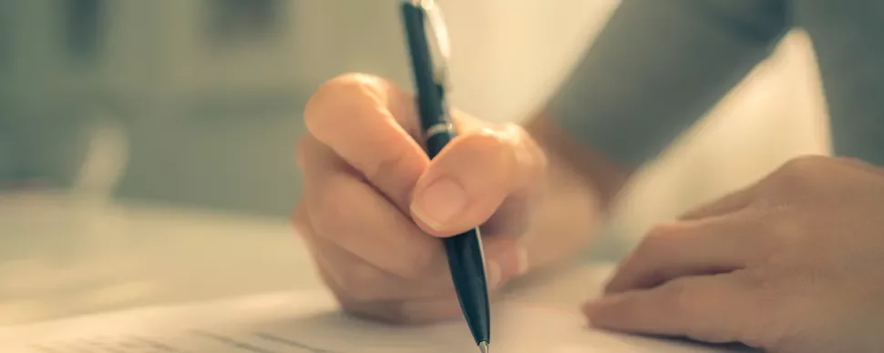 Person writing with a pen on paper.