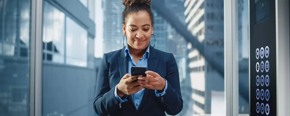 Person using smartphone in modern office elevator.