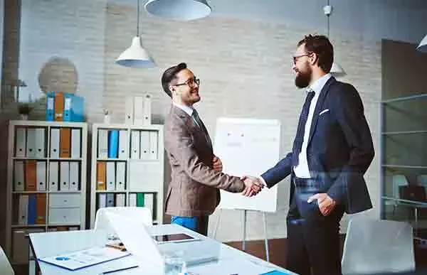 Two people shaking hands in a modern office setting.