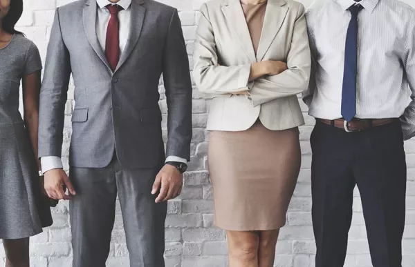 People in business attire standing against a brick wall