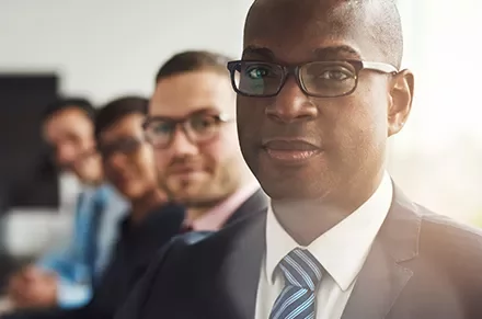 Group of professionals in suits with one person in focus.