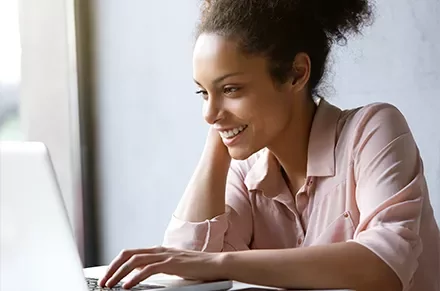 Person smiling while using a laptop.
