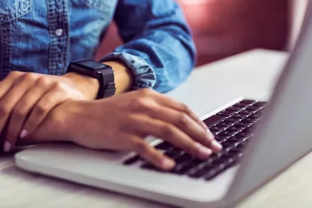 Person typing on a laptop wearing a smartwatch.