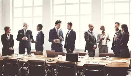 Group of people in business attire discussing around a table.
