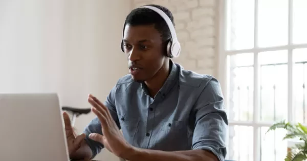 Person with headphones having a video call on a laptop.