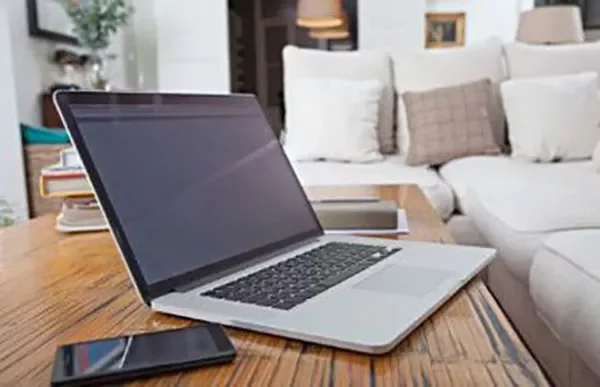 Laptop and smartphone on a wooden coffee table in a living room.